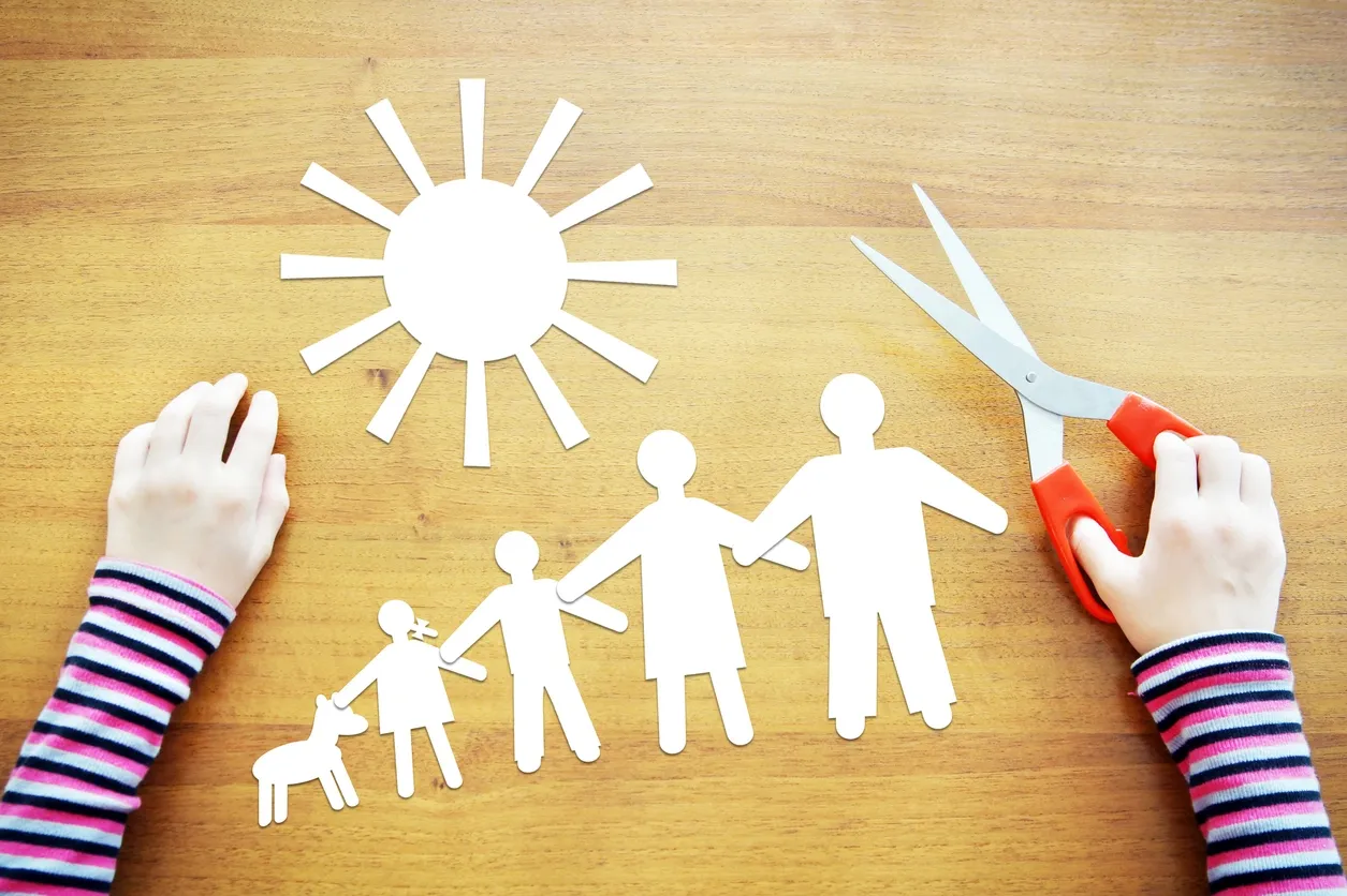 Hands crafting paper family and sun