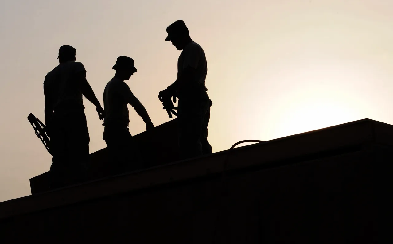 Silhouetted workers on rooftop at sunset
