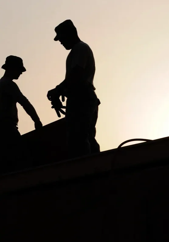 Silhouetted workers on rooftop at sunset